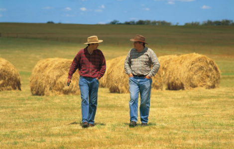 Two Australian farmers in front of hay bales